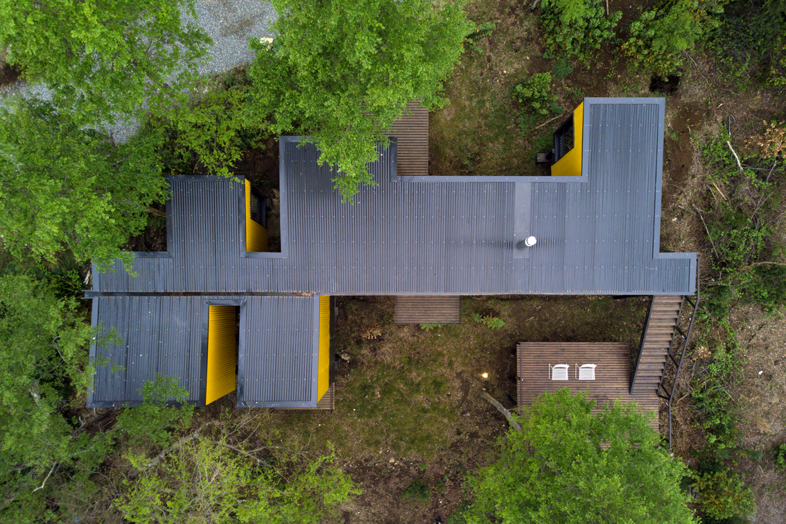 Yellow House — vista lateral del volumen elevado sobre pilotes, arquitecto Alejandro Soffia